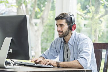 Gülümseyen sakallı Yakışıklı erkekler evde kulaklık dinleme şarkı koymak