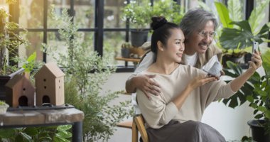 Yeşil evde oturan yaşlı çift, çocuklarla konuşurken, akıllı telefon konferans tutun