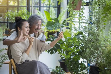 Yeşil evde oturan yaşlı çift, çocuklarla konuşurken, akıllı telefon konferans tutun