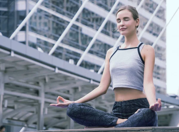 Güzel kadın meditasyon ve şehirde yoga yapıyor