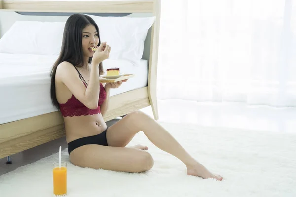 Asia charming woman sitting eating cake and relax drinking orange juice in bedroom.Relax time and lifestyle concept.