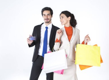 beyaz arka plan üzerinde kredi kartı ve alışveriş çantaları ile gülümseyen genç resmi çift