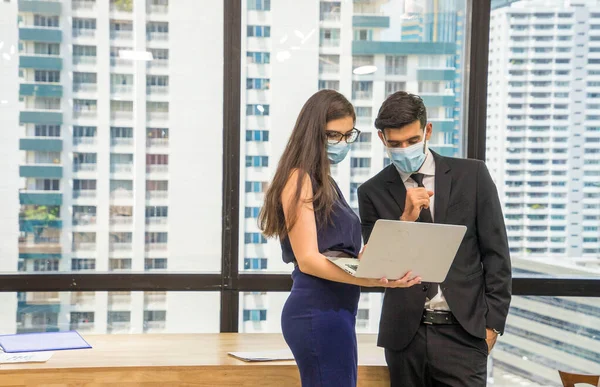 Female and Businessman workers meeting together with laptop and wear protective masks prevent PM 2.5 and corona virus or covic19 at co working space .Health and teamwork concept