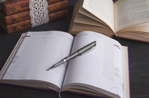 Book and black note with pen. Literature for the holidays and summer. Notes and quotes. Books on the dark table.