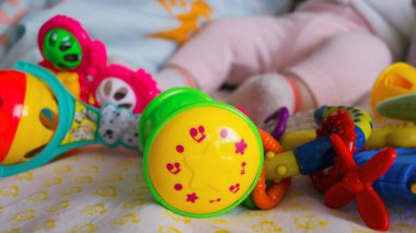 Hafif arka planda pek çok oyuncağın yanında küçük bacaklar. Çoraplı ve pantolonlu bacaklar. Çocuğun ayağında çıngıraklar. Yakın plan..