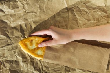 Kızın elinde buruşmuş el işi kağıdının arka planında turta var. Ev yapımı pişirme. Lahanalı büyükannenin turtaları. en üstteki görünüm