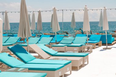 Deniz kenarındaki plaj kulübünde. Mavi şezlonglar, havuz kenarında şemsiyeler. Yaz mevsiminde deniz kıyısında.