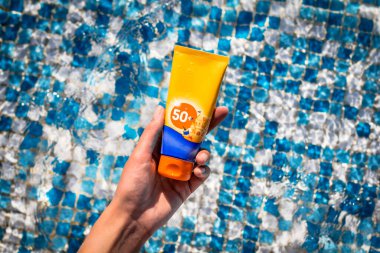 Genç bir kız havuzda 50 güneş kremi sıkıyor..