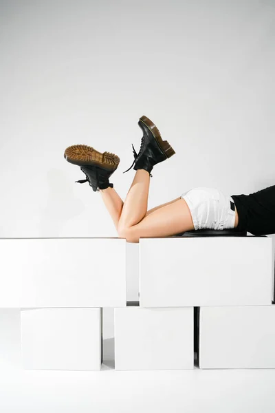 Ένα Κορίτσι Ξαπλώνει Μαύρα Παπούτσια Μεγάλα Ασπρόμαυρα Κουτιά Ελαφρύ Φόντο — Φωτογραφία Αρχείου