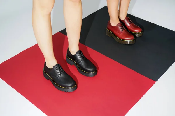 red and black leather derby on a colored background. girl's feet in eco-leather oxfords fashion shoes autumn winter 2020. new collection of shoes