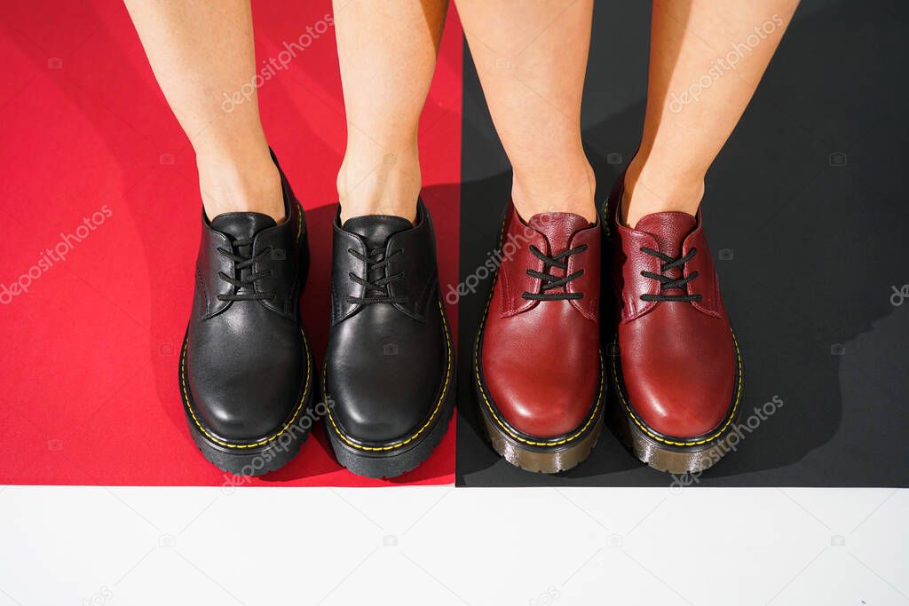  red and black leather derby on a colored background. girl's legs in eco-leather oxfords fashion shoes fall winter 2020.                              