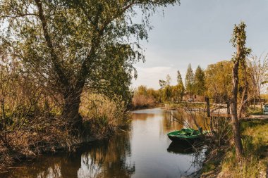 Tekne göldeki rıhtımda. Şehir ağaçlarının dışında, doğa nehrinin etrafında sessiz bir yer.