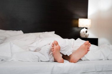 Bacakları beyaz bir battaniyenin altından dışarıyı gözetleyen bir adam oteldeki yorucu bir günün ardından sıkılır.