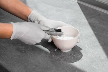 Beyaz koruyucu eldivenli bir kız saç boyasını oksitleyiciye sıkıştırıyor. İş yerindeki boyacı yakın plan saç bakım maskesinin saç boyası.