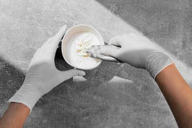 Beyaz koruyucu eldivenli bir kız saç boyasını oksitleyiciye sıkıştırıyor. İş yerindeki boyacı yakın plan saç bakım maskesi saç maskesinin üst görüntüsünü boyuyor.