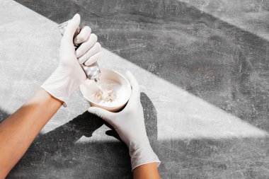 Beyaz koruyucu eldivenli bir kız saç boyasını oksitleyiciye sıkıştırıyor. İş yerindeki boyacı yakın plan saç bakım maskesinin saç boyası.