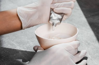 Beyaz koruyucu eldivenli bir kız saç boyasını oksitleyiciye sıkıştırıyor. İş yerindeki boyacı yakın plan saç bakım maskesinin saç boyası.