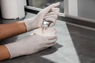 Beyaz koruyucu eldivenli bir kız saç boyasını oksitleyiciye sıkıştırıyor. İş yerindeki boyacı yakın plan saç bakım maskesinin saç boyası.