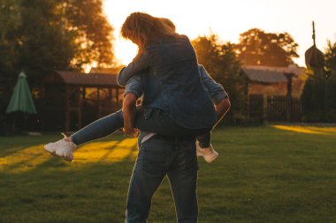 Genç çift dinleniyor ve doğada eğleniyor. Adam karısını sırtında yuvarlıyor.
