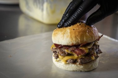 eldiven ile şef hamburger ekmek koyarak