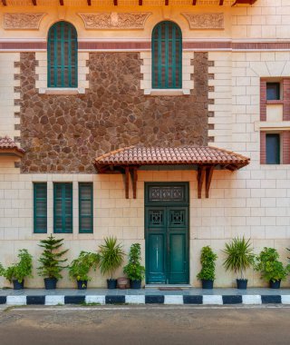 Kırmızı kiremit gölgelik yukarıdaki ile yeşil ahşap kapı ve pencere kepenkleri taş tuğla duvar, İskenderiye, Mısır ile Montaza genel Park'ta Saat Kulesi cephe