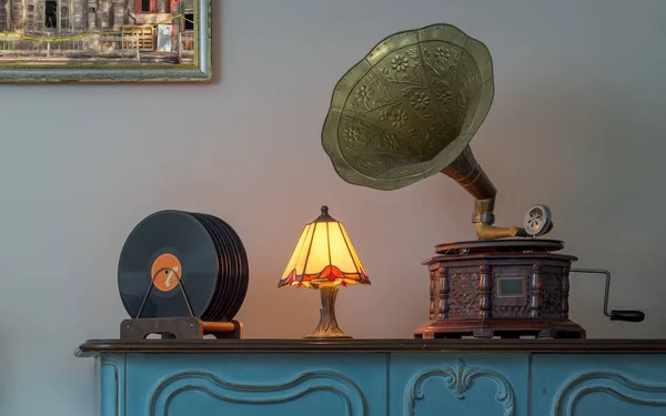 On dokuzuncu yüzyıl fonograf (gramofon) ve vinil kayıtlar bir ahşap masa ve arka plan bej duvar ve askı boyama