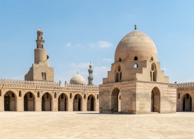 Courtyard of Ibn Tulun public historical mosque, Cairo, Egypt. View showing the ablution fountain, the minaret and the minaret of Sarghatmish mosque clipart