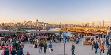 Istanbul, Türkiye - 25 Nisan 2017: Eminönü Piazza gıda arabaları satın ve deniz ürünleri restoranları Galata Kulesi ve Galata Köprüsü de dahil olmak üzere şehir manzaralı yüzen yerel vatandaşların ile gün batımına