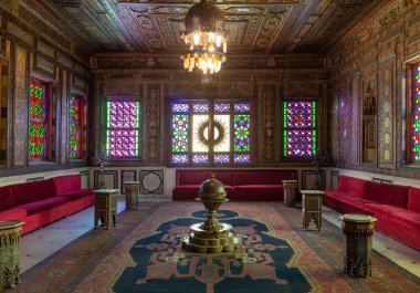 Cairo, Mısır - 2 Aralık 2017: Manial Sarayı, Prince Mohammed Ali. Suriye Hall ile süslü ahşap duvar ve tavan, pencere eşiği ile renkli vitray, süslü avize ve kırmızı kanepe
