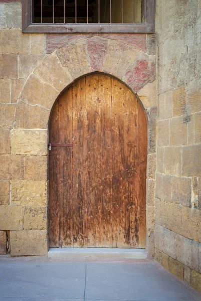 Old wooden door framed by arched bricks stone wall at the courtyard of al Razzaz historic house, Darb al Ahmar district, Old Cairo, Egypt