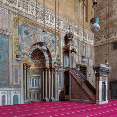 Colorful decorated marble wall with engraved Mihrab (niche) and wooden Minbar (Platform) at the Mosque and Madrassa (School) of Sultan Hassan, Cairo, Egypt clipart