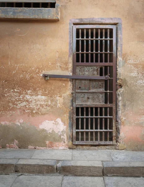 Closed rusted iron bars cell door and weathered grunge stone wall in closed abandoned prison at Cairo Citadel, Egypt