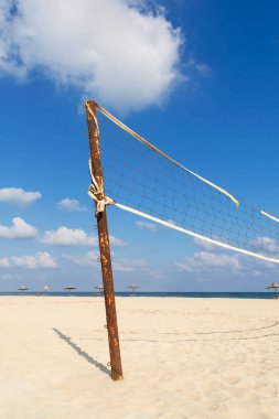 Yırtık voleybol net bulutlu mavi gökyüzü ve sabahları sarı kum ile sahilde