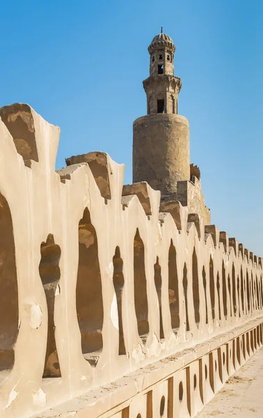 Ladrillos de piedra antigua valla decorada de la Mezquita de Ibn Tulun y minarete de la mezquita, El Cairo, Egipto — Foto de Stock
