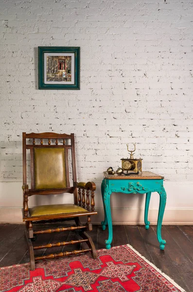 Кожаное кресло-качалка, деревянный зеленый винтажный стол и старинный золотой телефон на кирпичной стене — стоковое фото