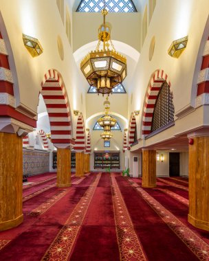 Ash Shaliheen Camii, Bandar Seri Begawan, Brunei Darussalam. Süslü altın avizeler, kırmızı desenli halılar ve çarpıcı çizgili kemerler. İslam mimarisi.