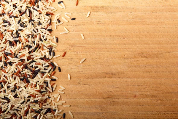 Mixed rice scattered on a wooden table. Healthy food, natural product.