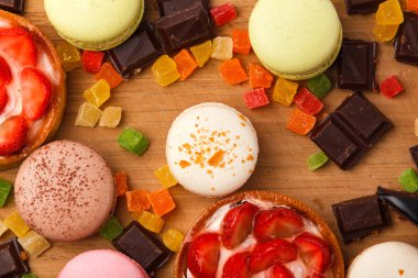 Tatlılar bir ahşap tahta üzerinde arka plan. Bademli kurabiye, kek, çikolata, çilek, şekerlenmiş meyve.