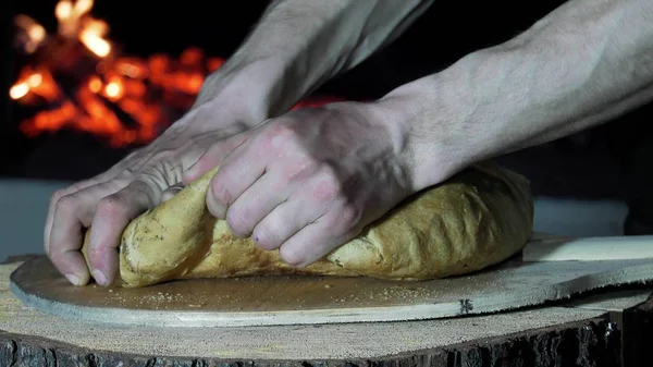パン屋を背景に焼きたてのパンを引き裂く男性の手 — ストック写真