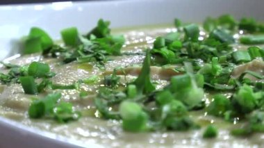 Seramik plaka yakın çekimde yeşillikli humus taze.
