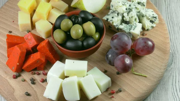 Cheese plate close-up with several varieties of fruit and honey cheese.