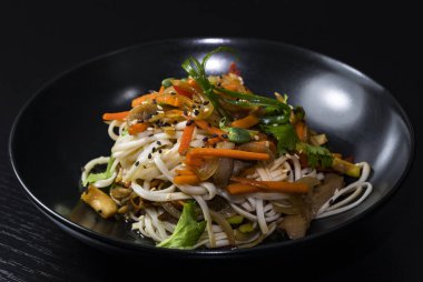 Siyah bir arka planda sebze ve et ile Asya noodle.