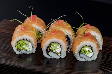 Deniz ürünleri ve balık, sebze, siyah bir arka plan üzerinde Japon geleneksel rulo.