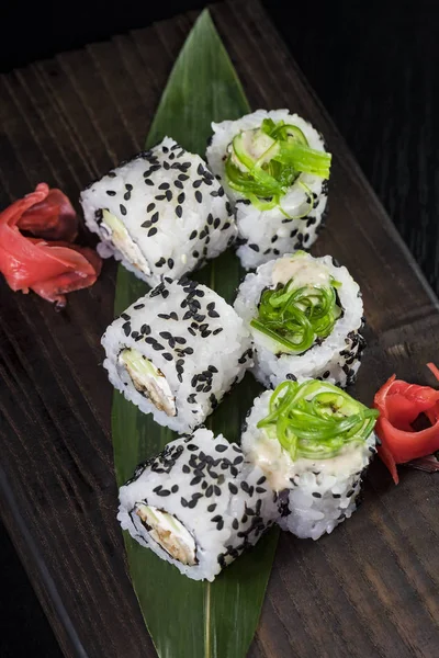 Deniz ürünleri ve balık, sebze, siyah bir arka plan üzerinde Japon geleneksel rulo.