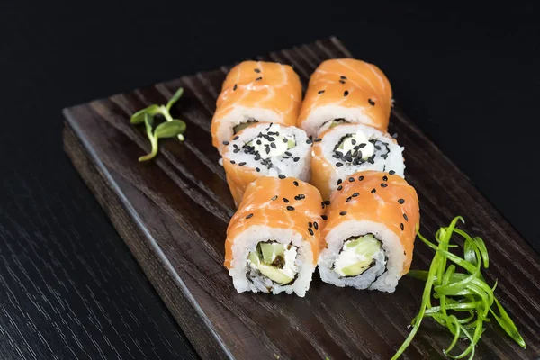 Deniz ürünleri ve balık, sebze, siyah bir arka plan üzerinde Japon geleneksel rulo.