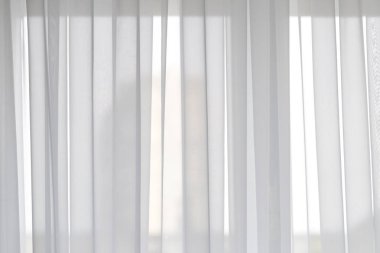 Pencerenin perdeleri beyaz kapakları ile mavi bir gökyüzü arka plana karşı rüzgar tarafından gelişmekte olan.