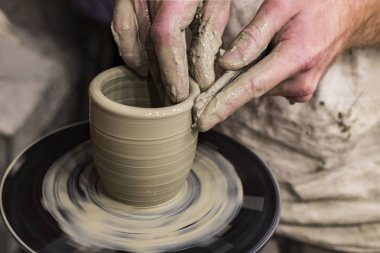 Bir çömlekçinin elleri, yakın plan çekilen kilden bir kupa yapar.