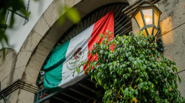 Мексиканский флаг, висящий над входом в здание с дугой — стоковое фото