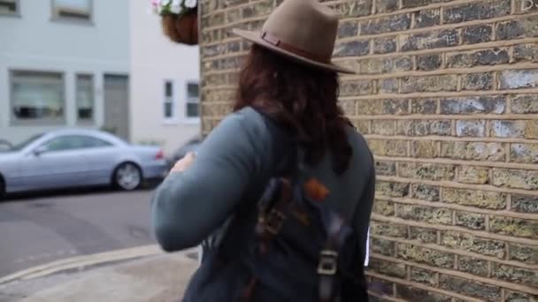 FHD donna con un cappello mette sul suo zaino e inizia a camminare per le strade — Video Stock