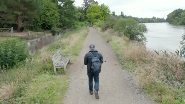 4k Aerial Shot of Man Walking Along Path next to River While Drone Spins Around — Stock video